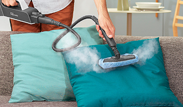 Das Bild zeigt den tragbaren Dampfreiniger Vaporetto Style von Polti im Einsatz auf einem Kissen