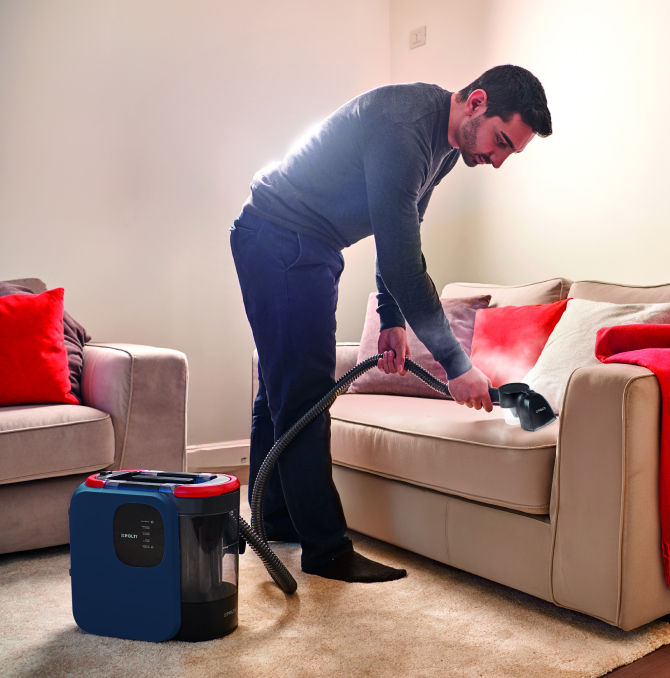 Ein Mann, der ein Sofa mit Dampf reinigt.