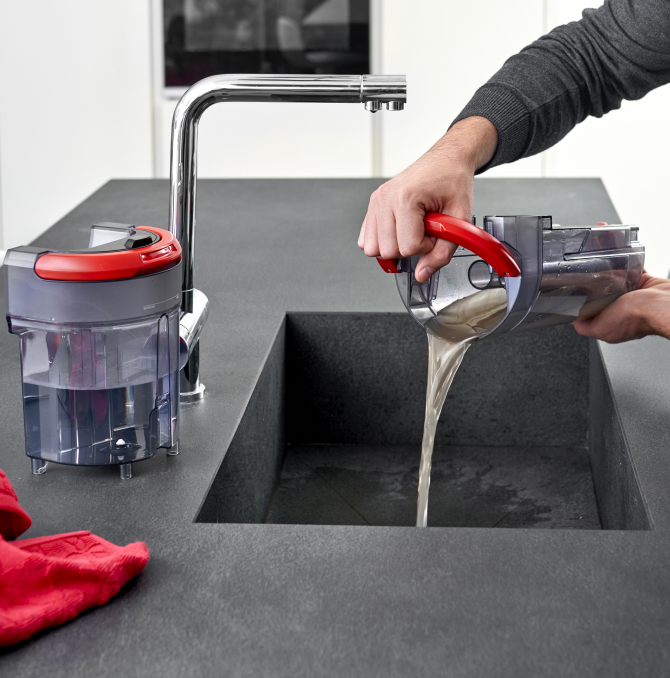 Ein Mann, der einen Tank mit schmutzigem Wasser in ein Waschbecken wirft.